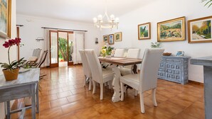 A dining area with a wooden table and chairs, a chandelier, and framed artwork on the walls. - Yourhouse Mon Repos 1 (Alcúdia)