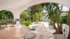 An outdoor patio with a round table, white chairs, and a potted plant. - Yourhouse Mon Repos 1 (Alcúdia)