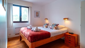 Une chambre à coucher avec un lit en bois, deux lampes de chevet, une table de chevet et une fenêtre avec des rideaux.