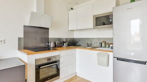A modern kitchen with white cabinets, stainless steel appliances, and a wooden countertop.