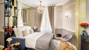 Ein modernes Schlafzimmer mit einem großen Bett, einem Nachttisch mit Dekoration, einem Sessel, einem Spiegel und einer Chandelier.