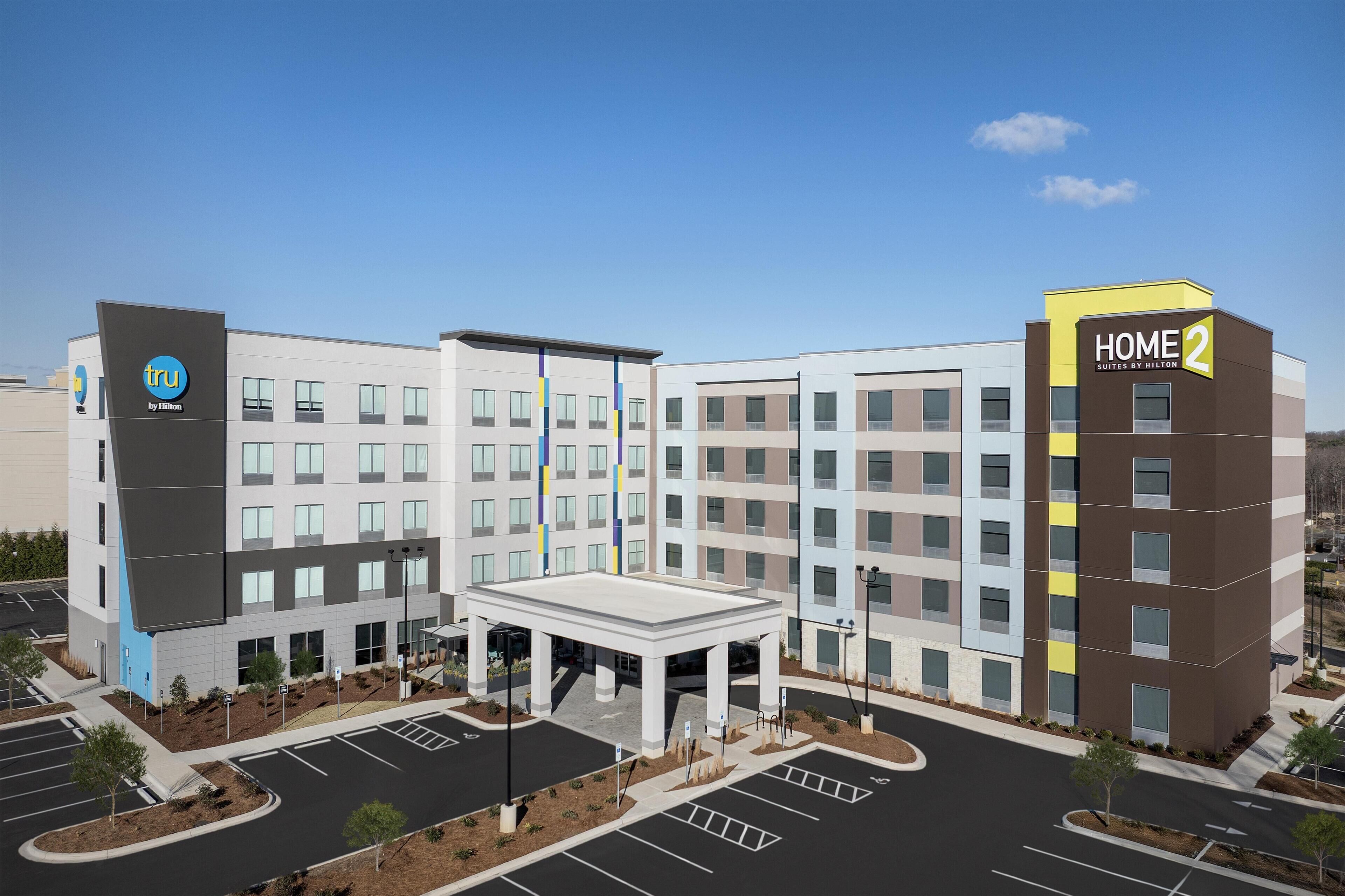 A modern hotel with a central courtyard, multiple floors, and a prominent 'HOME 2' sign.