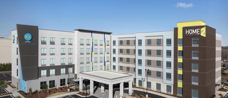 A modern hotel with a central courtyard, multiple floors, and a prominent 'HOME 2' sign.