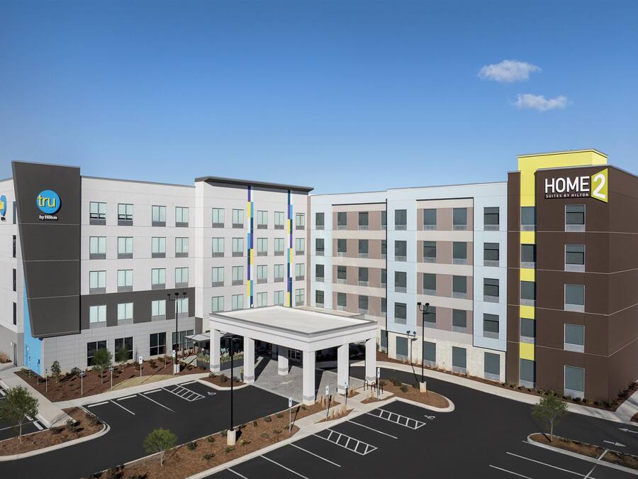 A modern hotel with a central courtyard, multiple floors, and a prominent 'HOME 2' sign.