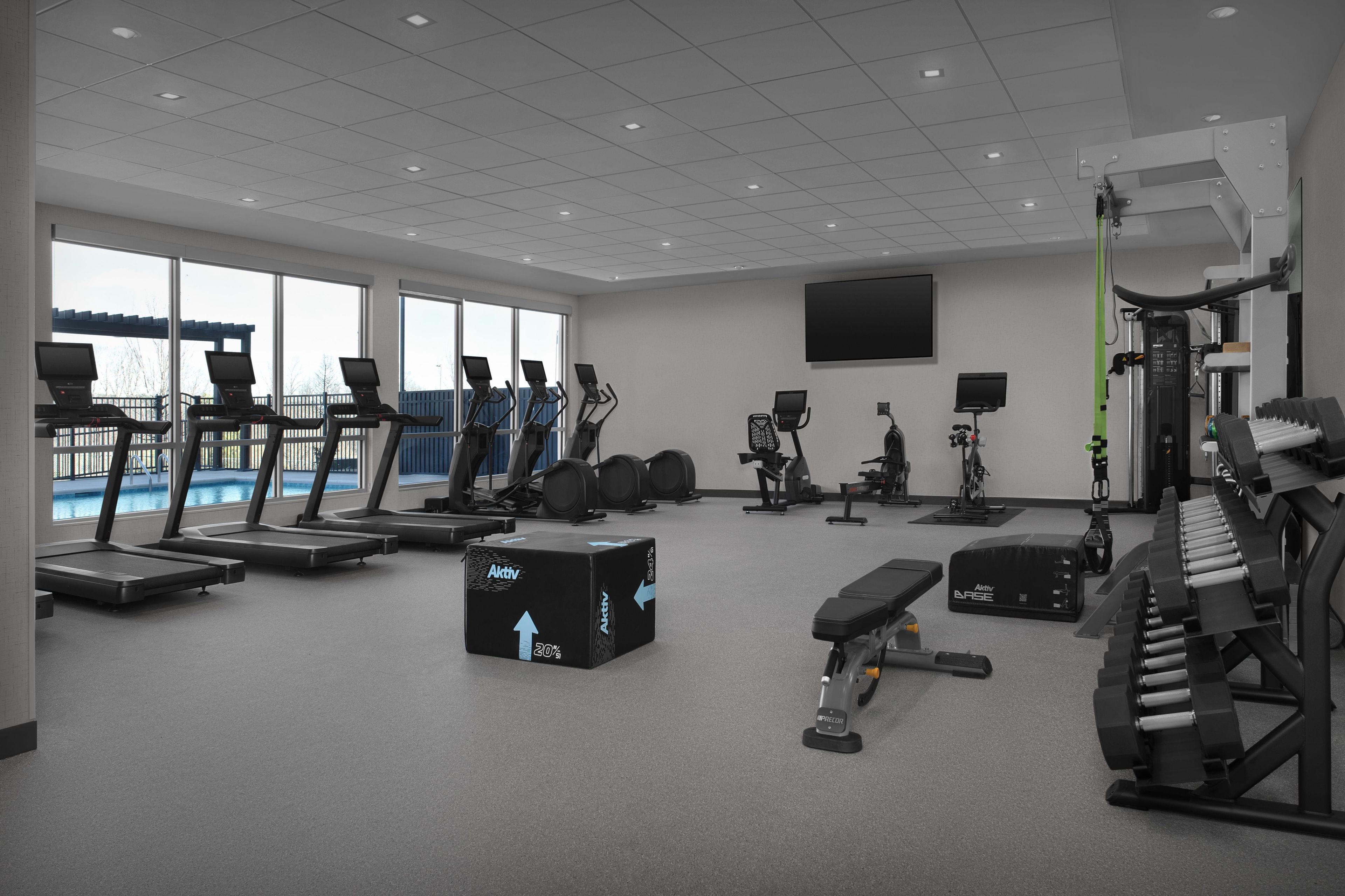 A modern gym with treadmills, stationary bikes, and weight equipment.