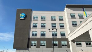 Un hôtel moderne, reconnaissable à son enseigne « tru by Hilton » bien visible, à ses nombreuses fenêtres et à son architecture épurée.