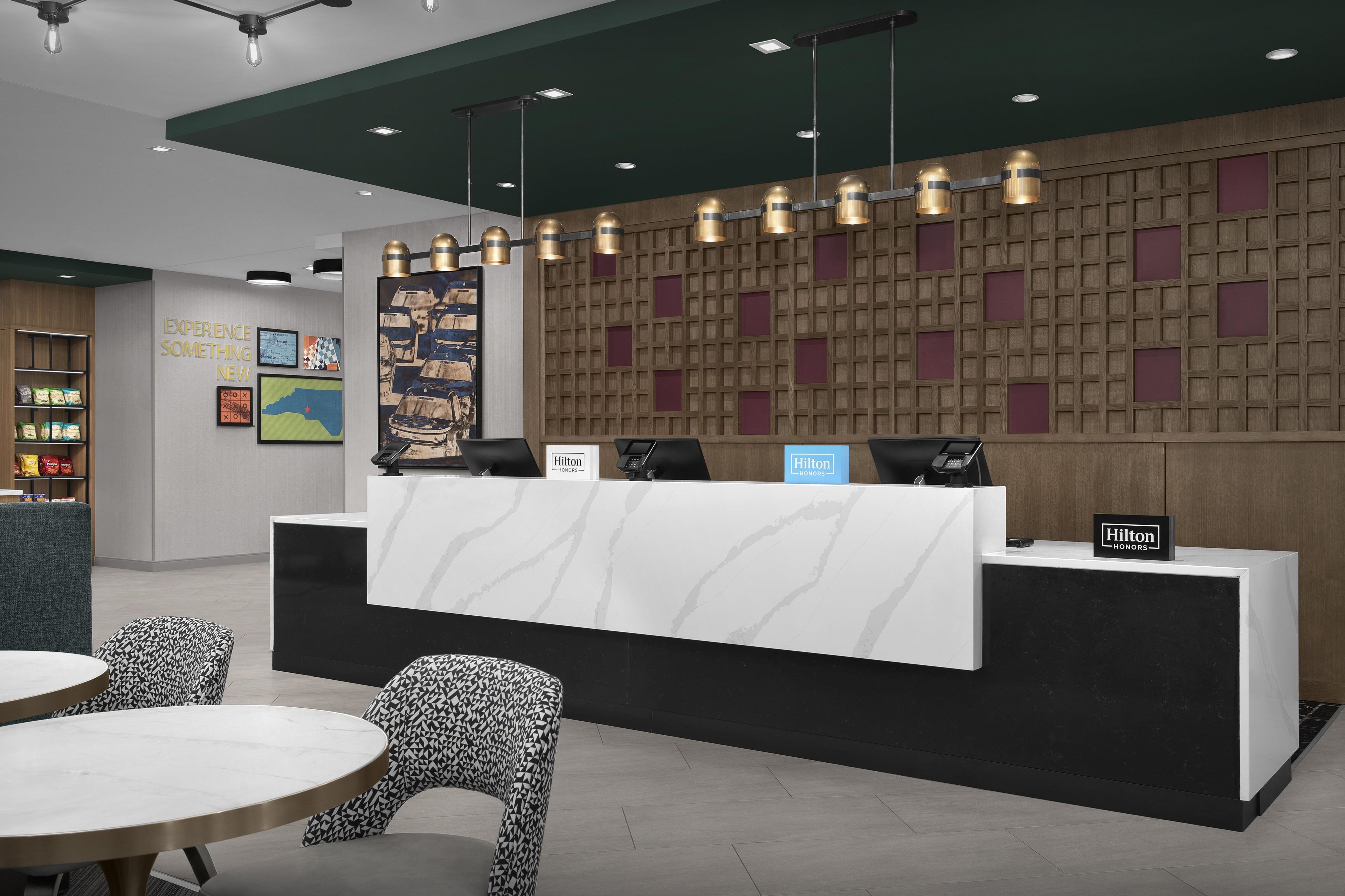 A hotel reception area with a marble counter, seating, and a wall with a grid pattern.