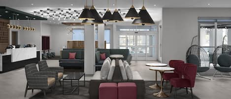 A modern hotel lobby with a reception desk, seating areas, and pendant lighting.