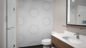 Une salle de bain moderne avec une douche à parois de verre, des toilettes blanches et un meuble-lavabo en bois avec un évier.
