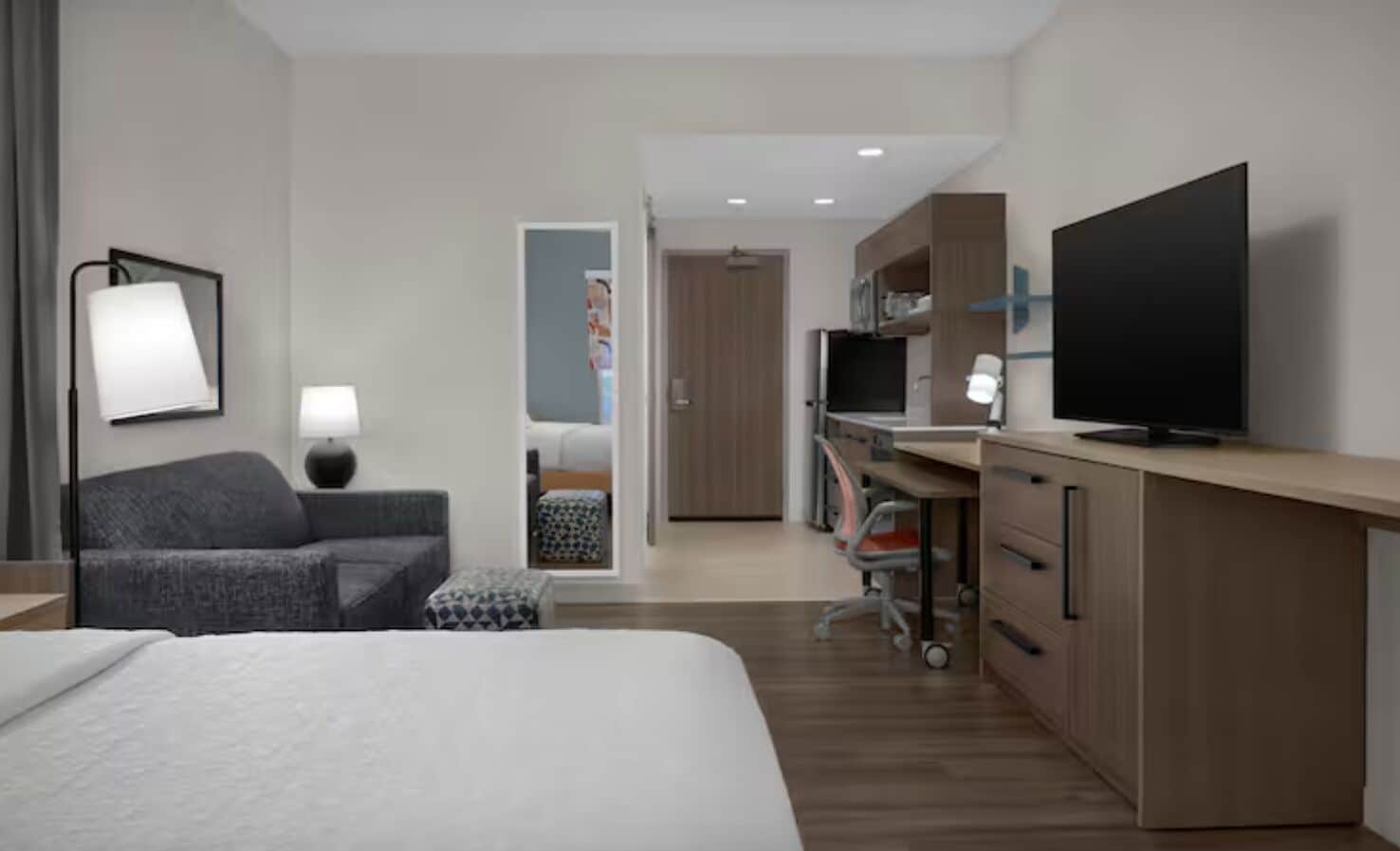 Una habitación de hotel moderna con una cama, un escritorio, un televisor y una zona de estar.