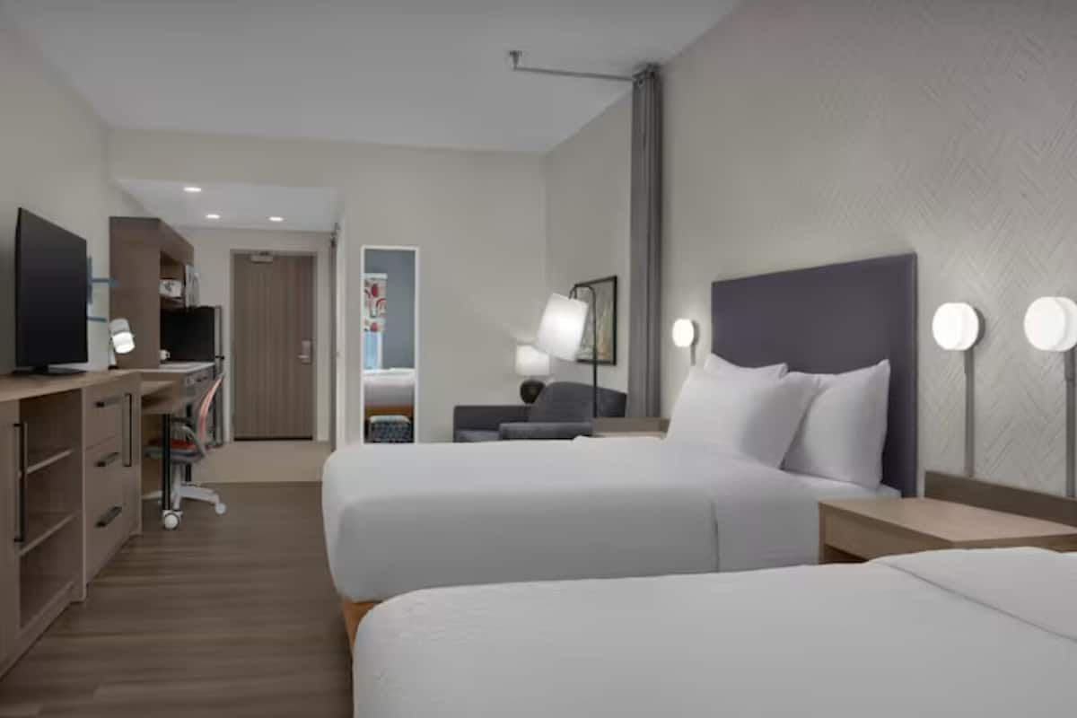 A hotel room with two beds, a desk, a TV, and a wardrobe.