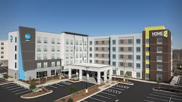 A modern hotel building with a central courtyard and multiple parking spaces.