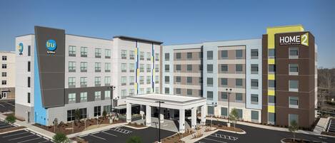 A modern hotel building with a central courtyard and multiple parking spaces.