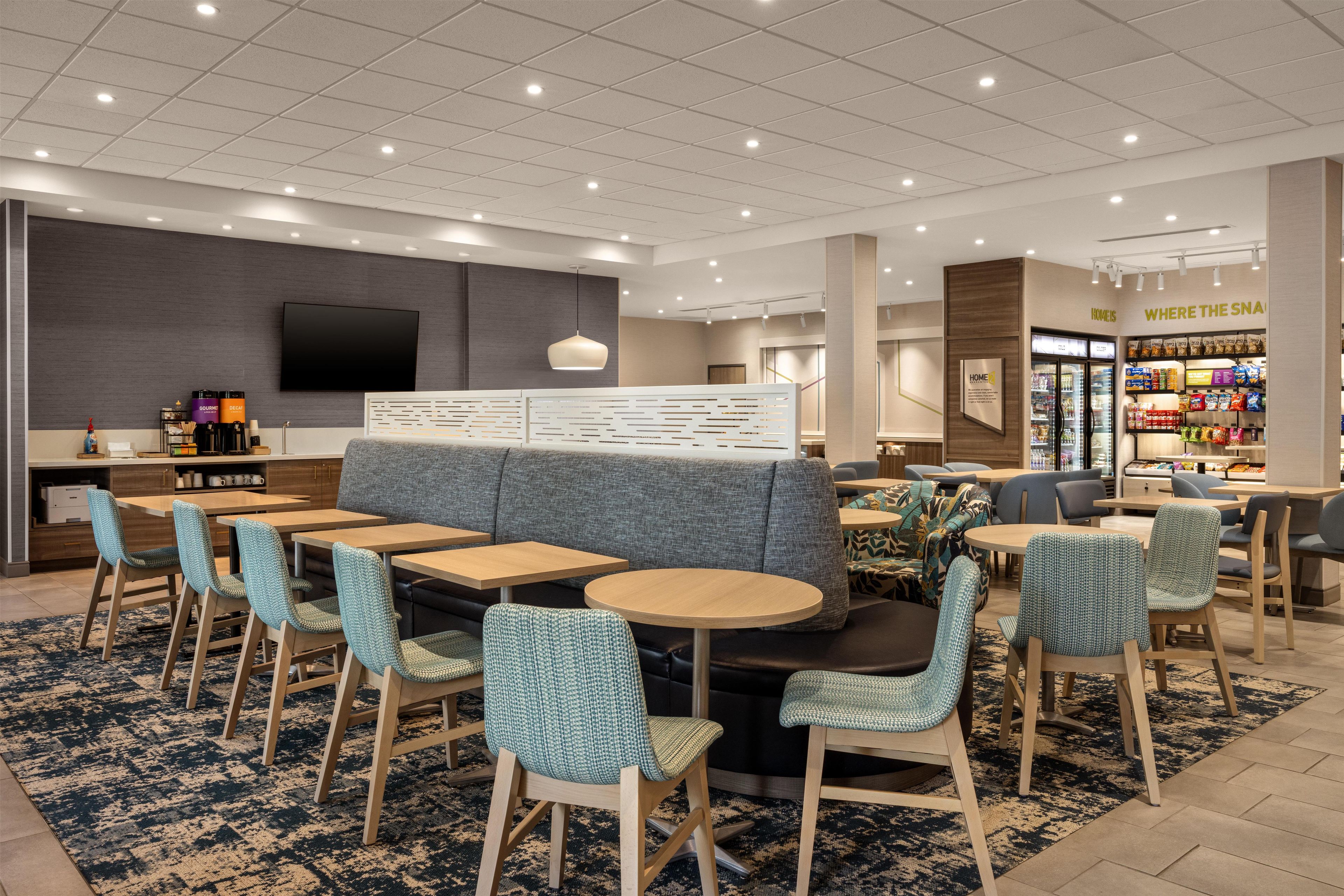 Un moderno vestíbulo de hotel con zonas de estar, una televisión y un bar de aperitivos.
