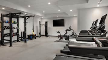 A gym with treadmills, weightlifting equipment, and a TV screen.