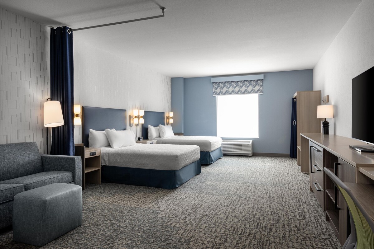 Une chambre d’hôtel comprenant un lit, deux tables de chevet avec des lampes, un canapé, un bureau et un téléviseur.