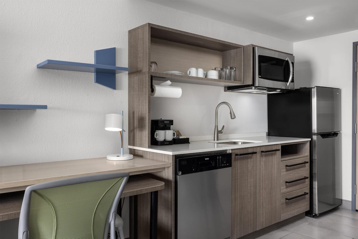 A modern kitchen with a dishwasher, a coffee machine, a microwave, and a refrigerator.