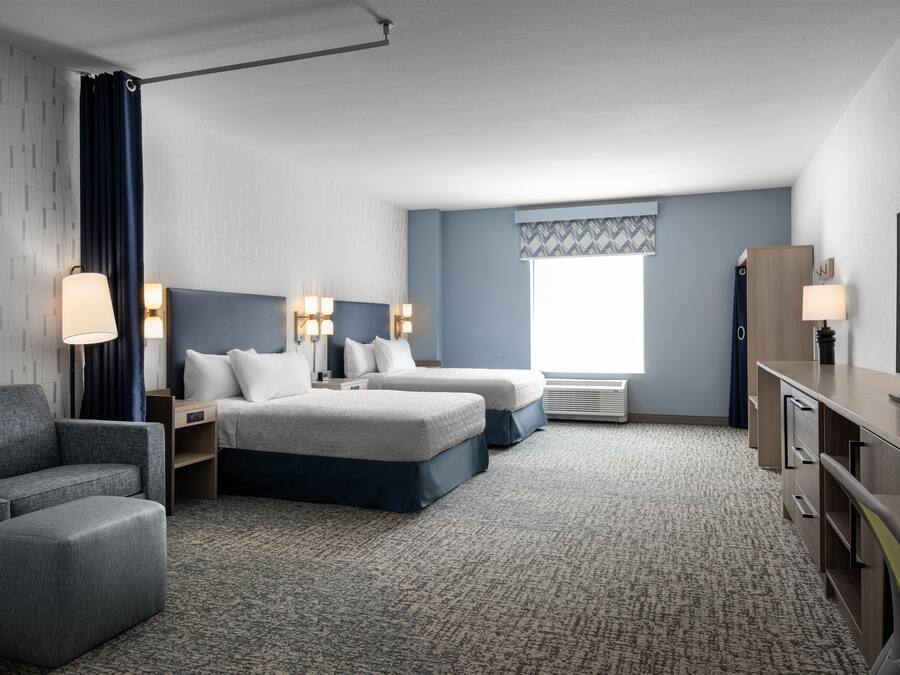 Ein Hotelzimmer mit einem Bett, zwei Nachttischen, einem Schreibtisch, einem Stuhl und einem Fernseher.