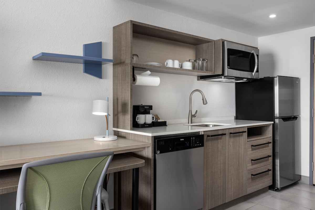 A modern kitchen with a dishwasher, a coffee machine, a microwave, and a refrigerator.