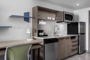 Een moderne keuken met een vaatwasser, een koffieapparaat, een magnetron en een koelkast.