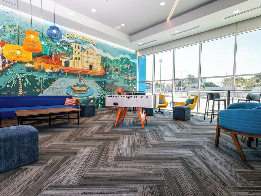 A modern lounge area with a large mural, comfortable seating, and a foosball table.