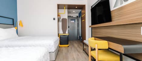 Una habitación de hotel con cama, escritorio, silla, televisor y armario.