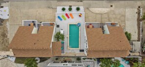 A rooftop pool area with a central swimming pool, surrounded by lounge chairs and umbrellas. - Heated Pool Steps to Beach, Cherry Grove Sleeps 24 (North Myrtle Beach)