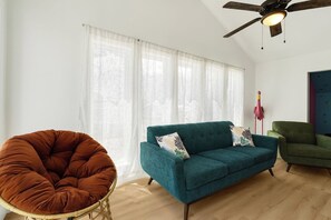A room with a teal sofa, a brown chair, and a ceiling fan. - Heated Pool Steps to Beach, Cherry Grove Sleeps 24 (North Myrtle Beach)