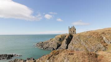 A historic stone castle on a rocky cliff overlooking the sea.