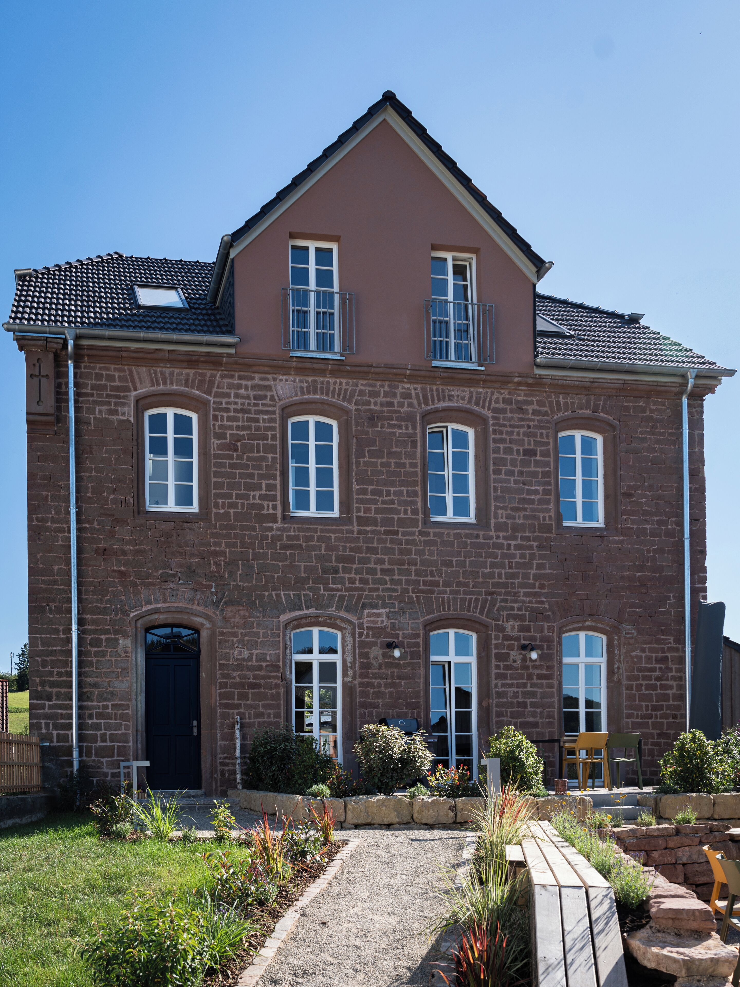 A two-story brick house with a symmetrical facade, multiple windows, and a front door.