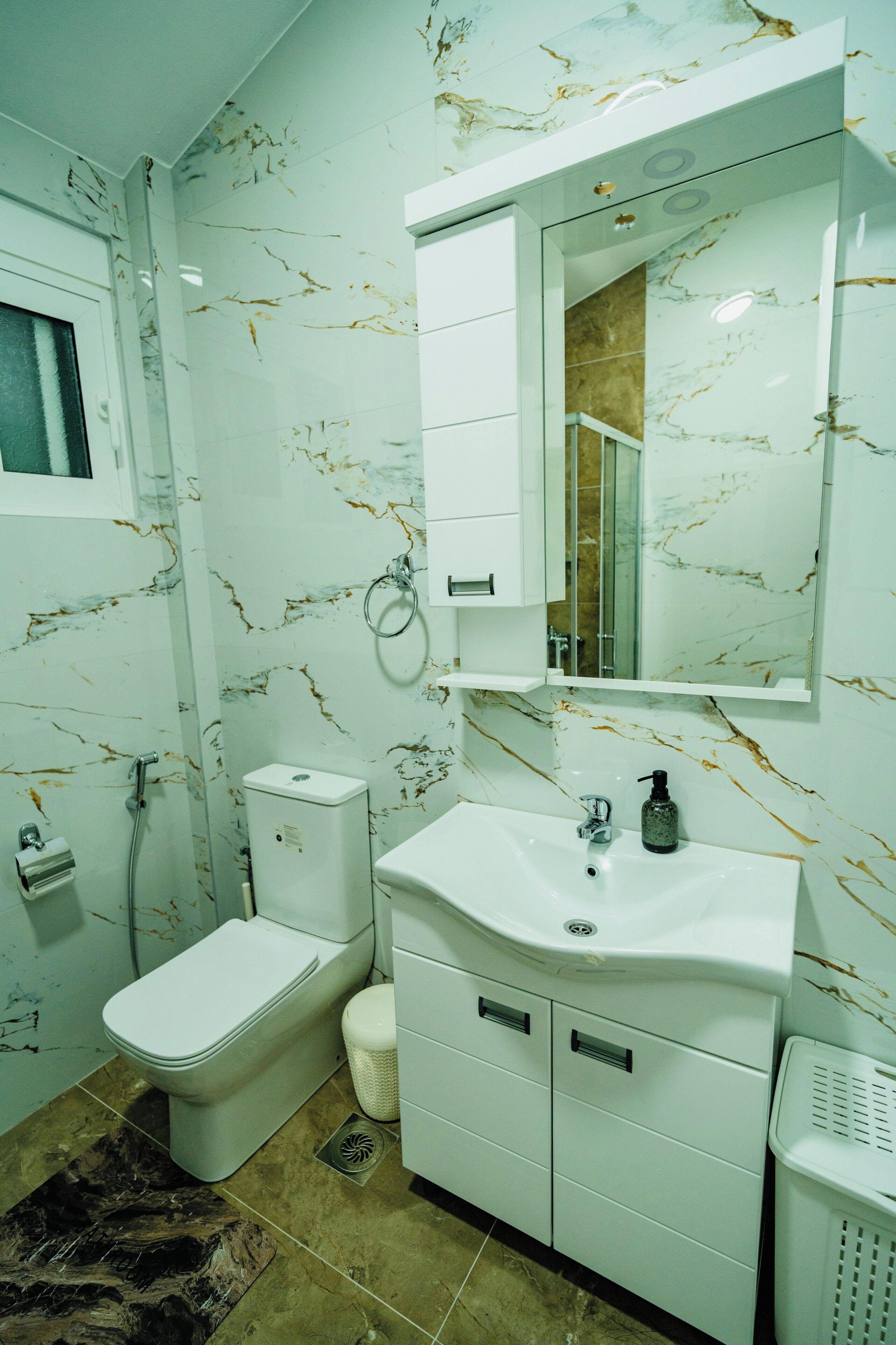 Une salle de bain équipée de toilettes, d’un lavabo, d’un miroir et d’une douche.