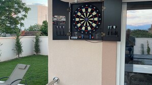 Un dardo fijado en una pared, un área de patio con sillas y una puerta de cristal que da al exterior.