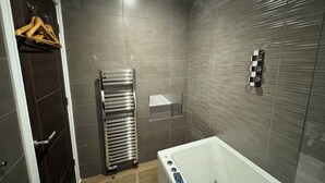 Un baño moderno con una bañera, un perchero para toallas y un panel de control de la ducha.