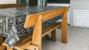 Un coin repas avec un banc et une table en bois, une cuisine avec un dosseret carrelé et une porte-fenêtre coulissante.