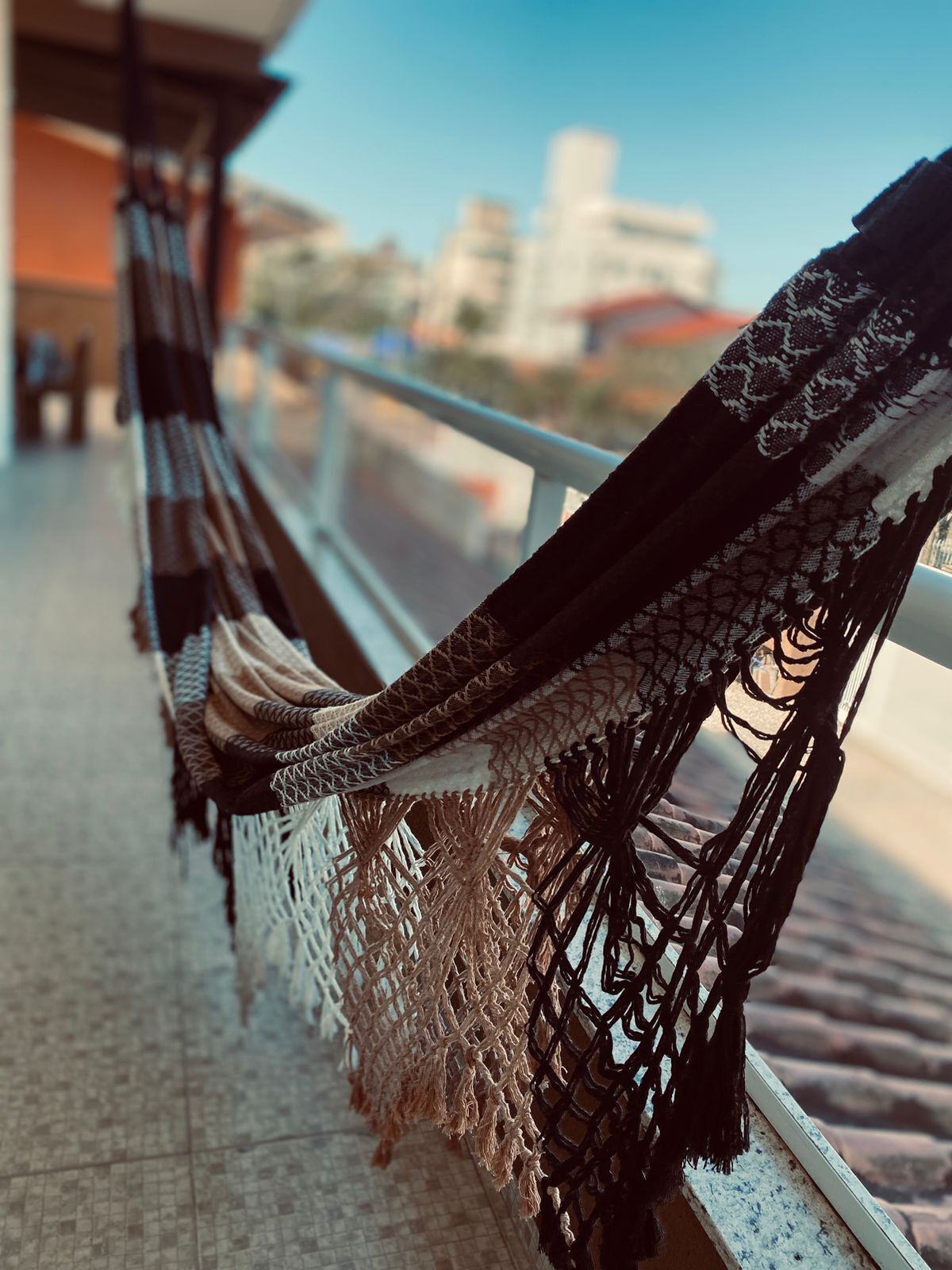 A hammock with a woven pattern, attached to a balcony railing.