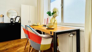 A dining area with a wooden table, chairs, a vase with flowers, and a window with a view. - Bright and Spacious Room Near Kaufpark Alterlaa (Vienna)