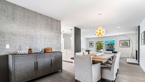 Eine moderne Küche mit grauer, strukturierter Spritzschutzwand, einem dunkelgrauen Schrank und einem Holzespeisetisch mit sechs Stühlen.