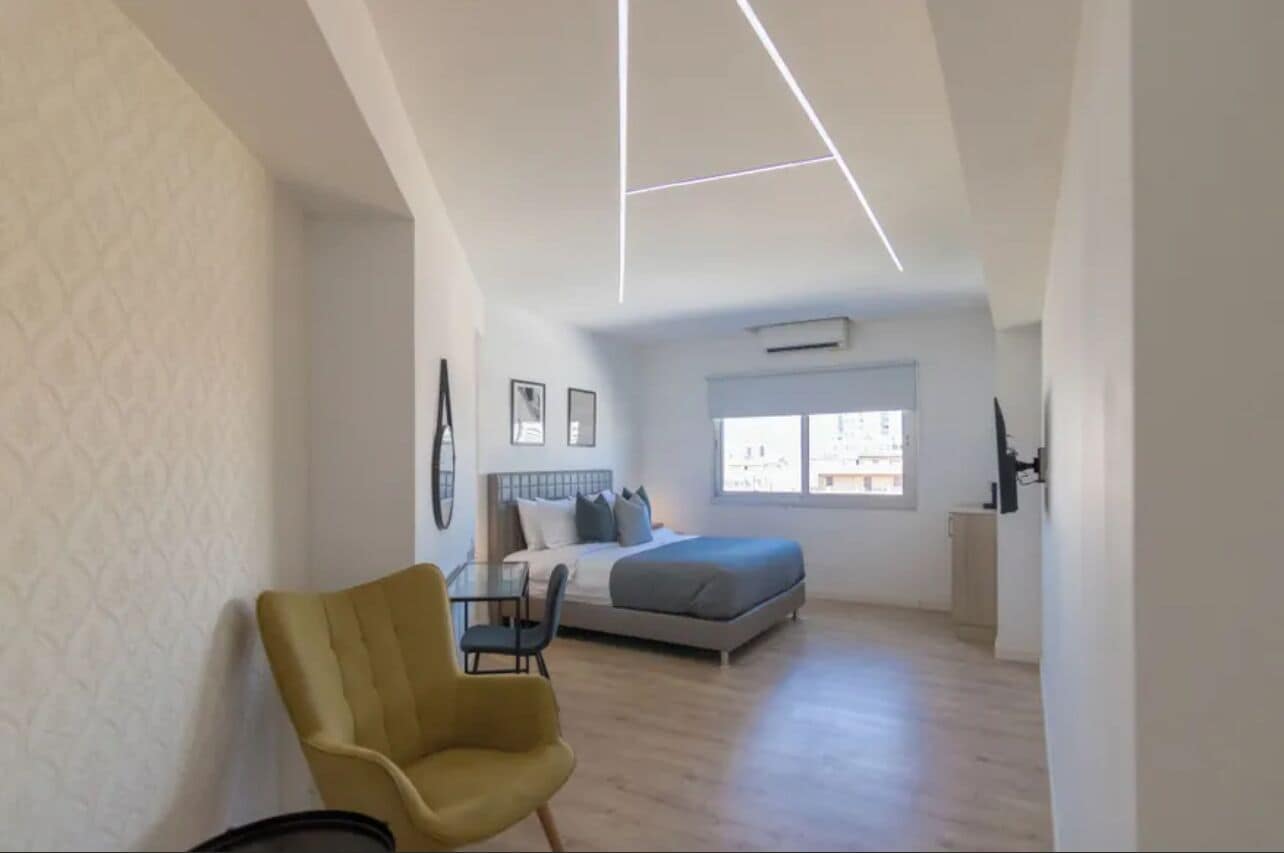 Un dormitorio moderno con cama, mesita de noche y una silla.