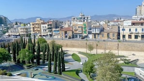 A cityscape with a variety of buildings, including residential and commercial structures. There is a clear sky and distant mountains. - Plateia Suite Grigio (Nicosia)