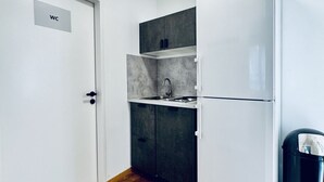 Une petite cuisine équipée d’un évier, de placards et d’un réfrigérateur.