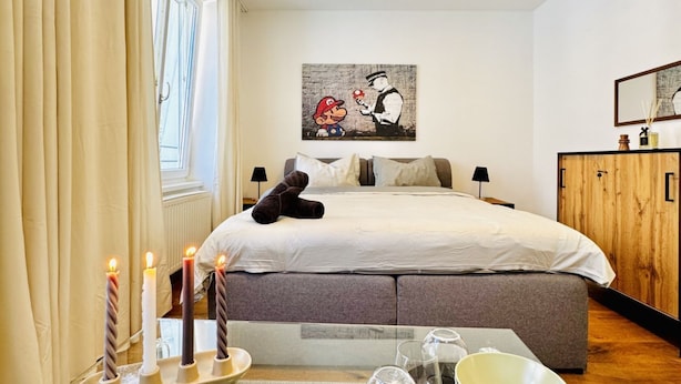 Une chambre d’hôtel avec un lit, des lampes de chevet, une armoire en bois et un tableau au mur.