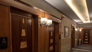 Een hotelgang met houten deuren, een gestreept tapijt en wandlampen.