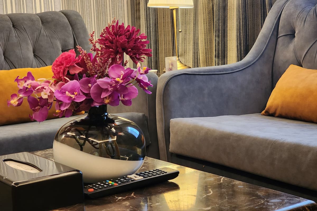 A modern living room with a sofa, a coffee table, a lamp, and a vase of flowers.