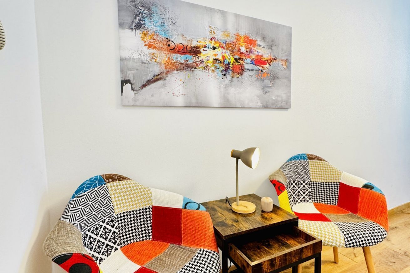 Ein Zimmer mit zwei Stühlen, einem kleinen Tisch und einem Bild an der Wand.
