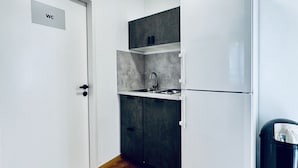 Una pequeña cocina con un lavabo, armarios y un refrigerador.