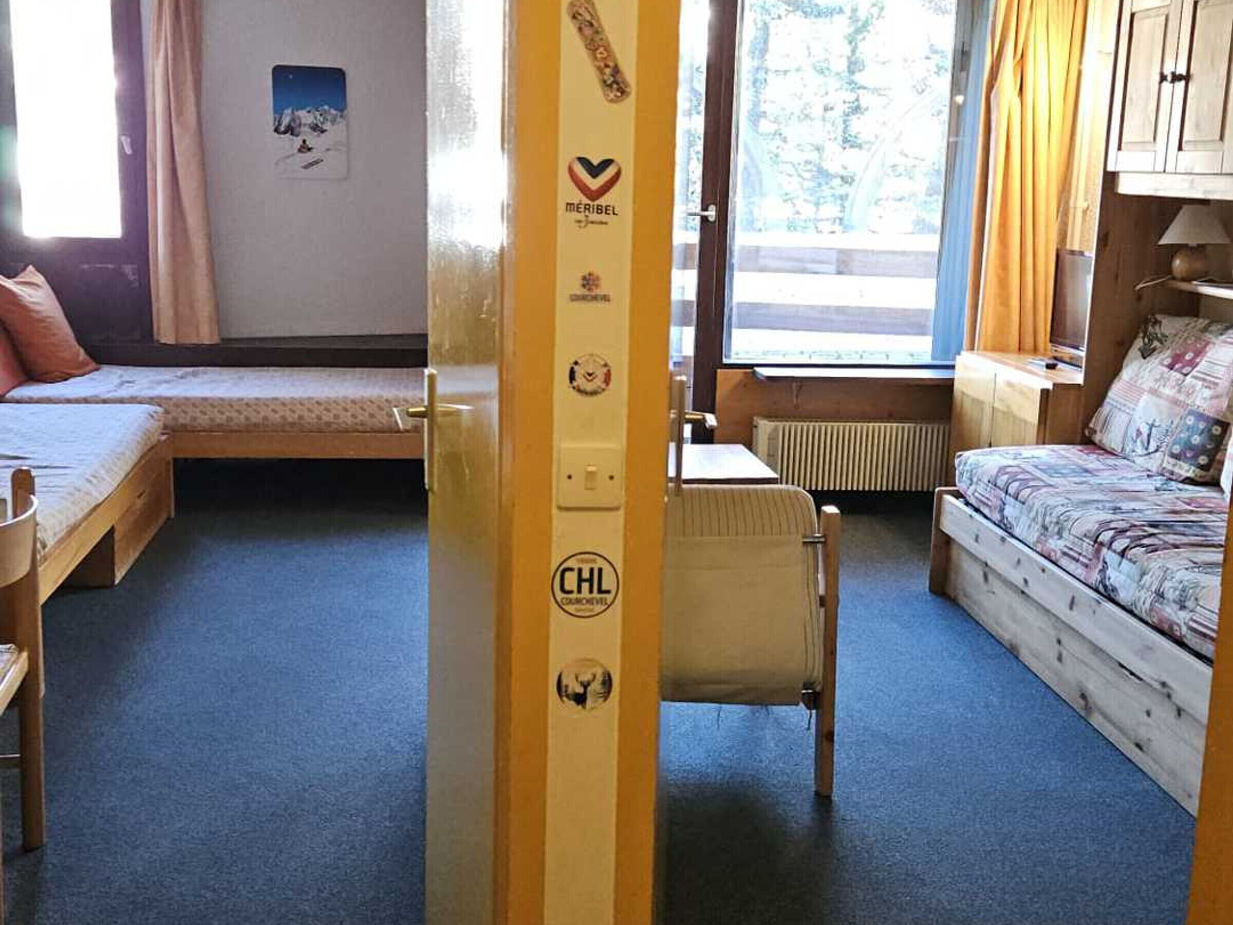 A dormitory room with two beds, a radiator, and a window with curtains.