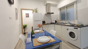 Une cuisine moderne équipée d’un lave-linge intégré, un coin repas avec une table bleue et une fenêtre offrant une belle vue.