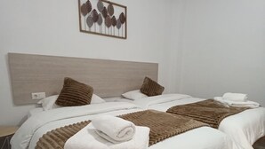 Une chambre d’hôtel avec un grand lit, deux oreillers, une tête de lit, une œuvre d’art accrochée au mur et une serviette pliée posée sur le lit.