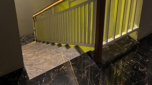 Un escalier avec une main courante en bois et une balustrade en verre, menant à un niveau inférieur.