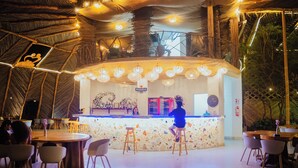 An indoor bar area with a counter, stools, and tables. - Samay Playas (Playas)